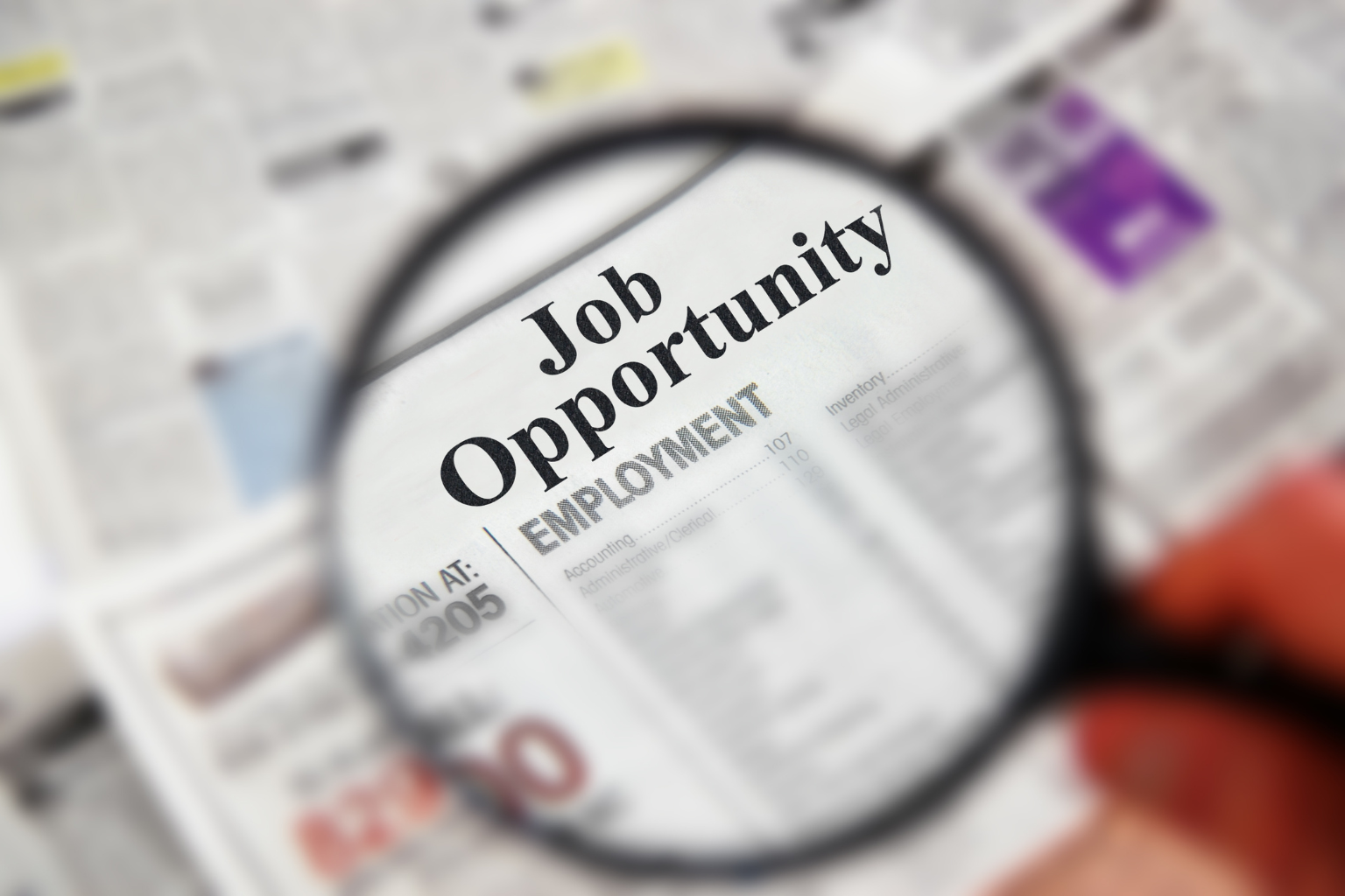 Magnifying glass highlighting a newspaper job ad, symbolizing new ESA job posting requirements in Ontario.